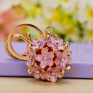 Detail view of pink enamel flower ball keychain with gold accents on a book