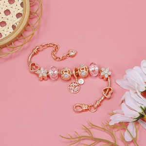 Detailed view of a rose gold charm bracelet featuring a Tree of Life pendant and floral charms