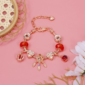 Detailed macro view of rose gold crown and heart charms on a snake chain bracelet