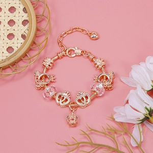 Macro view of rose gold charm bracelet featuring crown, heart pendants and crystal beads