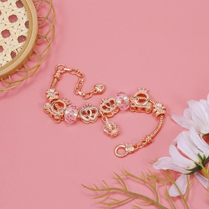 Macro shot of rose gold charm bracelet with crown, pumpkin coach, and pink glass beads