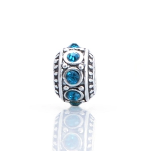 Macro view of silver charm bead with sky blue crystals and vintage embossed patterns