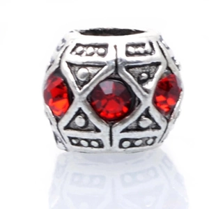 Detailed view of vintage silver bead with red rhinestones and geometric engravings