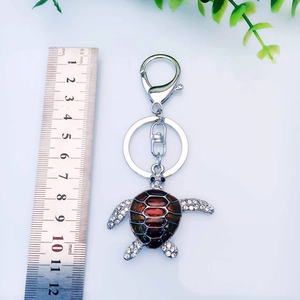 Turtle keychain with red enamel shell and sparkling rhinestones on white background