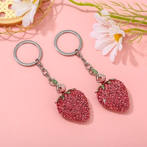 Detail of two sparkling pink strawberry keychains with rhinestones and silver rings