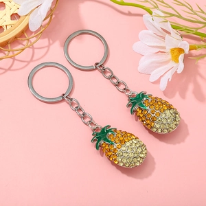 Macro shot of two pineapple keychains with yellow rhinestones and green enamel leaves