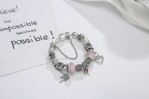 Détail d'un bracelet à breloques flamant rose et palmier avec perles en argent ciselé