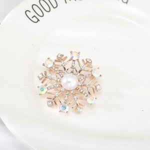 Broche flocon de neige en perles avec cristaux brillants sur un plateau en céramique