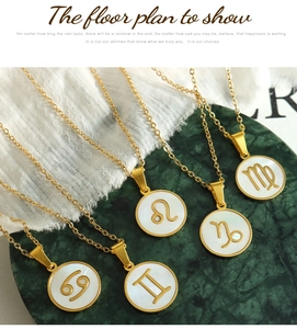 Detail view of five gold zodiac necklaces with white shell pendants on marble texture