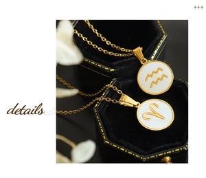 Detail shot of gold zodiac necklaces with white shell inlay on black velvet jewelry box