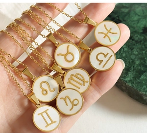 Macro shot of gold zodiac pendants with white sea shell inlay on tarnish-free steel chains