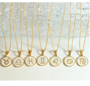 Detailed flat lay of gold zodiac pendants with white mother-of-pearl inlay on O-chains