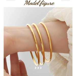 Three stackable gold titanium steel bangles with polished finish worn on female wrist