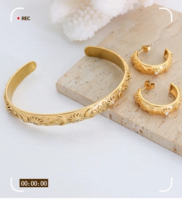Macro detail of gold celestial bracelet and earrings set with star and moon embossing