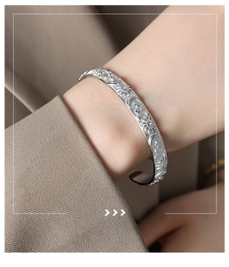Detailed view of silver celestial star and moon embossed motifs on a brushed steel bangle