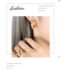 Detail of gold C-shaped earrings with celestial patterns and layered pearl ring set