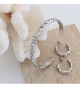 Detail of silver celestial bangle and C-earrings set with sun and moon relief engravings