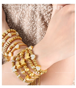 Detail of gold-tone multi-layer bracelet featuring butterfly and heart charms with crystals