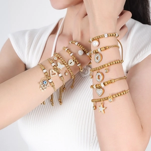 Bohemian gold beaded bracelet set featuring heart, butterfly, and Evil Eye charms