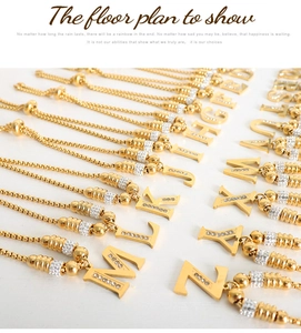 Detail van gouden letterhangers met strass-steentjes aan verstelbare kettingen