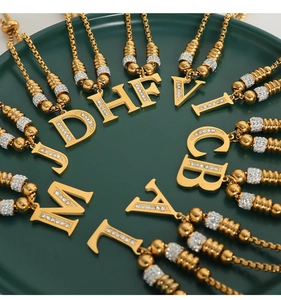 Detail van vergulde letterhangers met kristallen op een donkergroen dienblad
