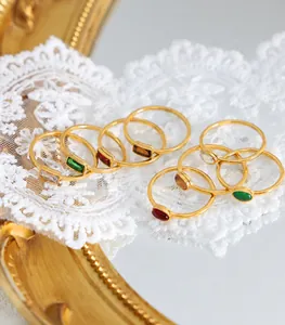 Close-up of vintage stackable gold rings with emerald and ruby glass stones on lace
