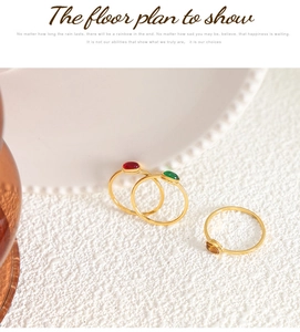 Detailed view of three gold titanium rings with red, green, and amber zircon gemstones