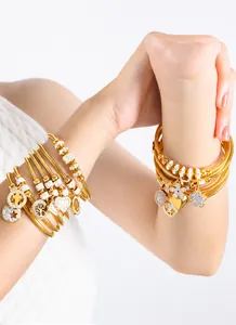 Detalle de una pulsera multicapa dorada con dijes de estrella, corazón y cruz