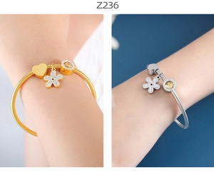 Detalle de pulseras de cadena de serpiente con dijes de corazón y flor en oro y plata