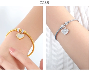 Detalle de colgantes de corazón en oro y plata en pulseras de cadena de serpiente con circonitas
