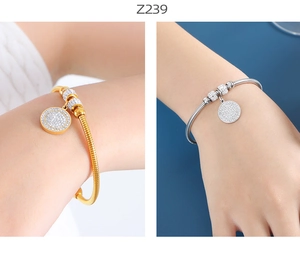 Detalle de pulseras de cadena de serpiente doradas y plateadas con dijes de circonitas
