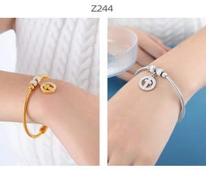 Primer plano de brazaletes de moda con dijes de cruz pavé en acabados dorado y plateado