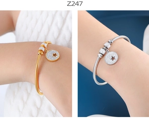 Detalle de pulseras de oro y plata con colgantes de estrella y piedras de circón