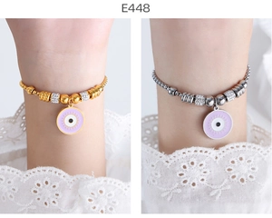 Detail of 18K gold and silver evil eye bracelets with lavender enamel on wrist