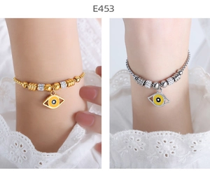 Detail view of 18K gold and silver beaded bracelets with yellow evil eye charms