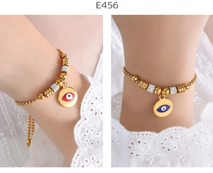 Detail of gold beaded bracelets featuring Evil Eye charms with red and blue accents