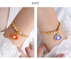 Macro detail of 18K gold-plated bracelets featuring evil eye charms and beaded textures