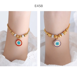Detail of gold 18K evil eye bracelets with red and purple enamel charms on snake chains
