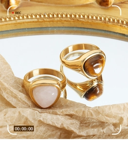 Detail of vintage 18k gold plated rings featuring tiger eye stone on textured background
