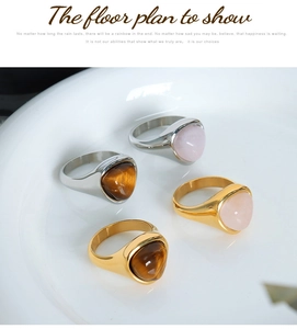 Close-up of heart-shaped tiger eye stone and rose quartz on 18k gold-plated steel rings