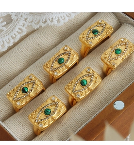 Dettaglio macro di anelli placcati in oro 18K con motivo a occhio verde e cristalli