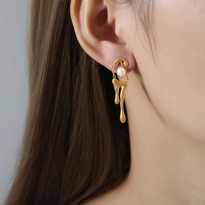 Orecchini vintage in oro 18k con design a metallo fluido e perla indossati da modella