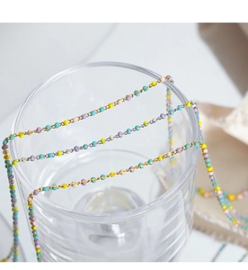 Detalle macro de cuentas de esmalte de colores en cadenas O de acero de titanio oro y plata