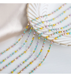 Detalle de collar de cuentas coloridas hecho a mano con cadenas de oro y plata en plato cerámico