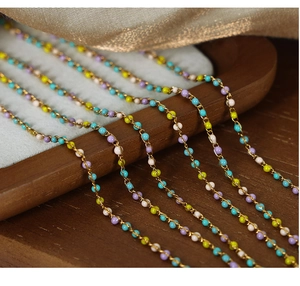 Primer plano de collares de cuentas coloridas con cadenas doradas y piedras esmaltadas