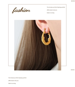 Détail de créoles dorées à texture organique portées par un mannequin dans un style mode