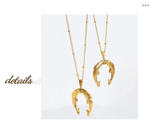 Détail de pendentifs double dauphin dorés sur un collier à chaîne perlée polie