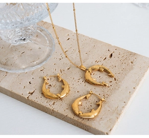 Gros plan d'un ensemble collier et boucles d'oreilles dauphin plaqué or 18 carats