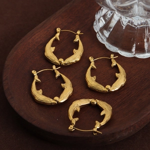 Boucles d'oreilles queue de baleine dorées avec finition métal brossé sur plateau bois