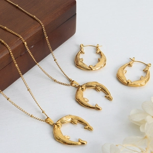Parure collier et boucles d'oreilles dauphin dorés sur fond de bois blanc rustique